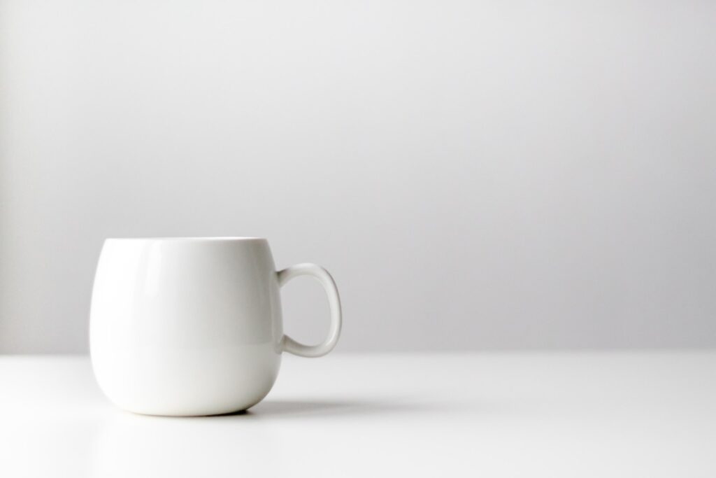 White mug sat on a white desk.